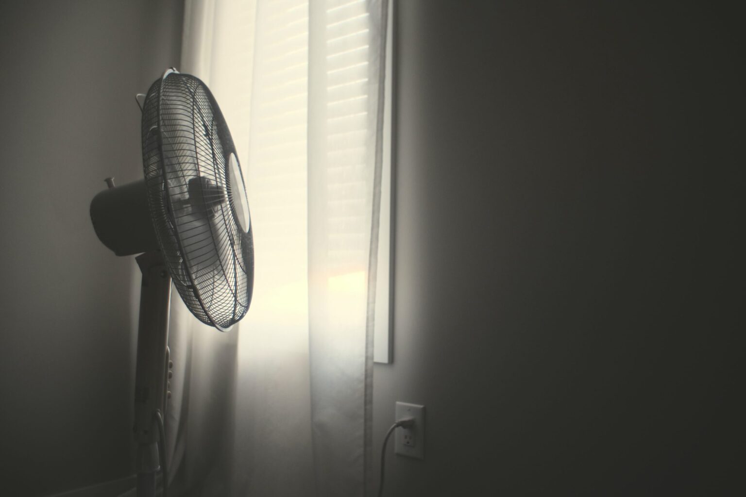 pedestal fan blowing a long curtain