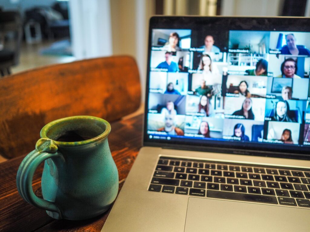 a laptop screen showing a group video call, with a drinking mug to the side of the laptop