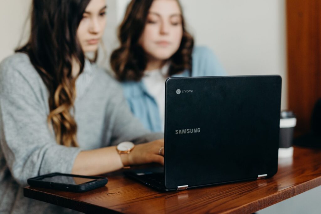 two young women working at a laptop
