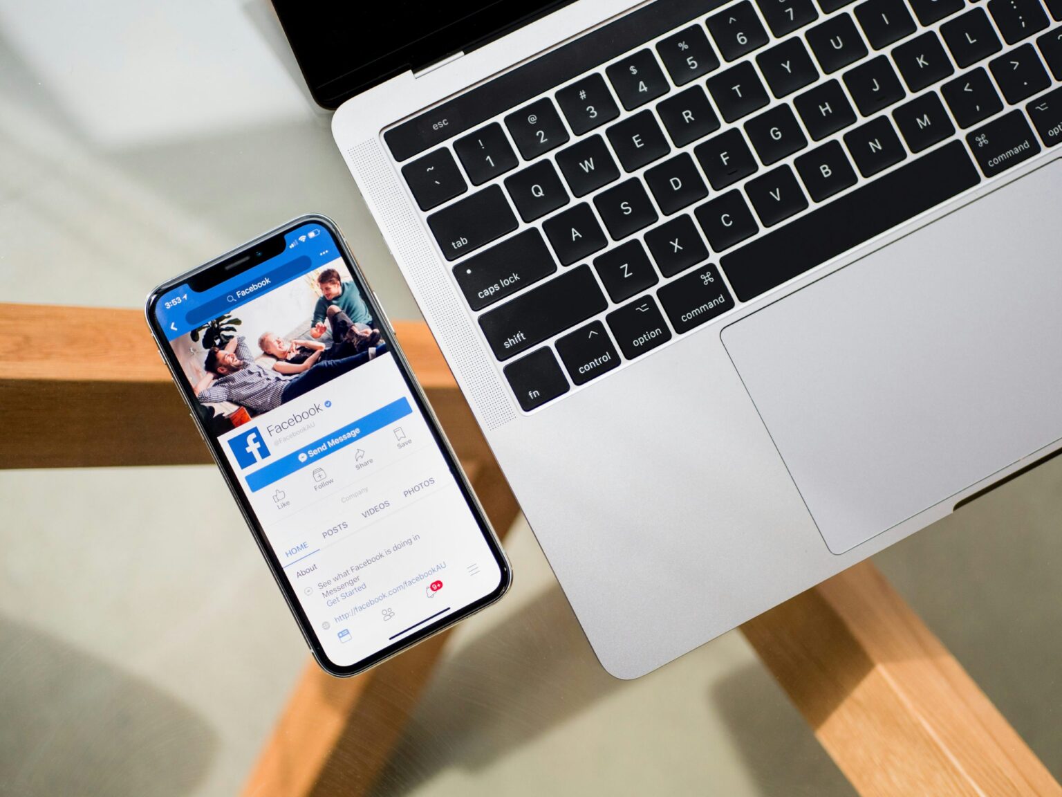 a phone displaying Facebook, next to a laptop