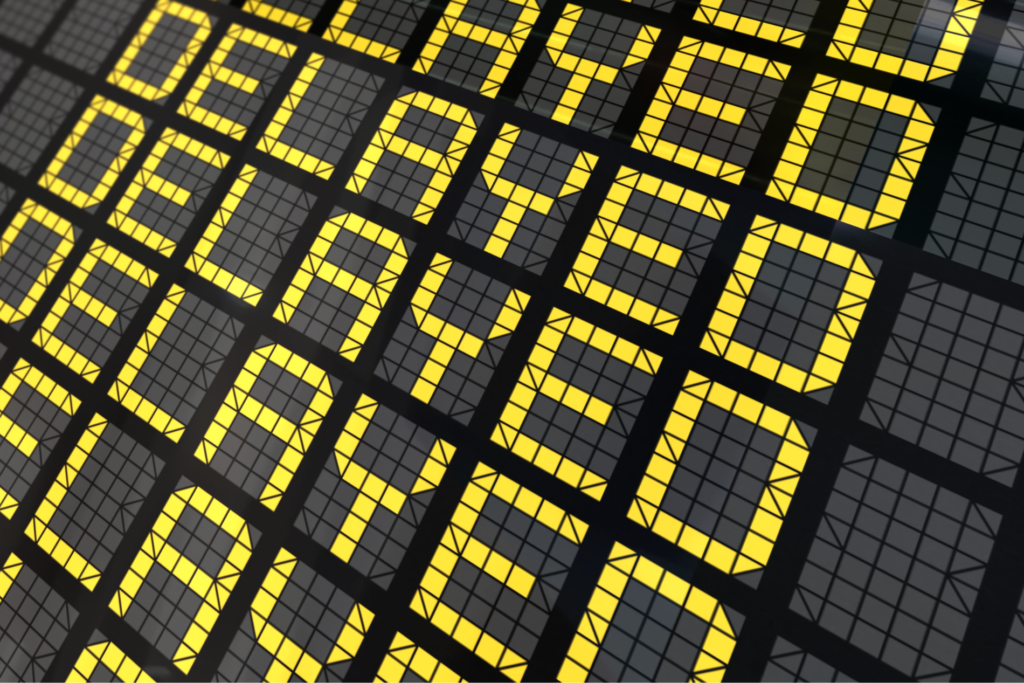 an airport departure flip sign that reads "delayed"
