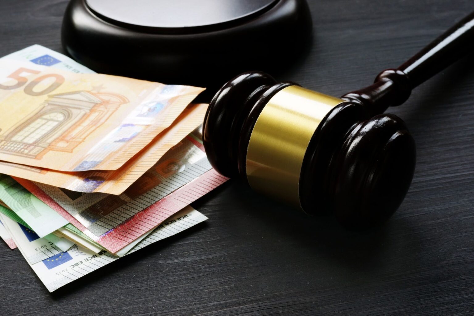 a judges gavel is pictured next to a pile of euros