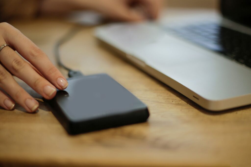 an external hard drive on an office desk, connected to a laptop