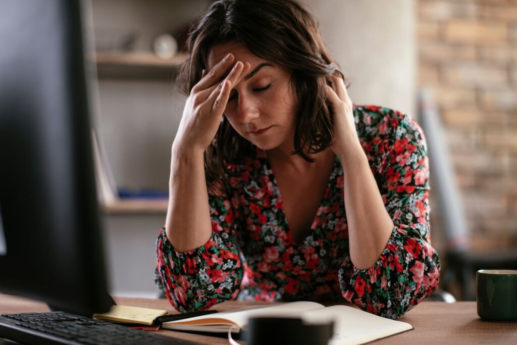 a tired and fatigued woman at her computer desk